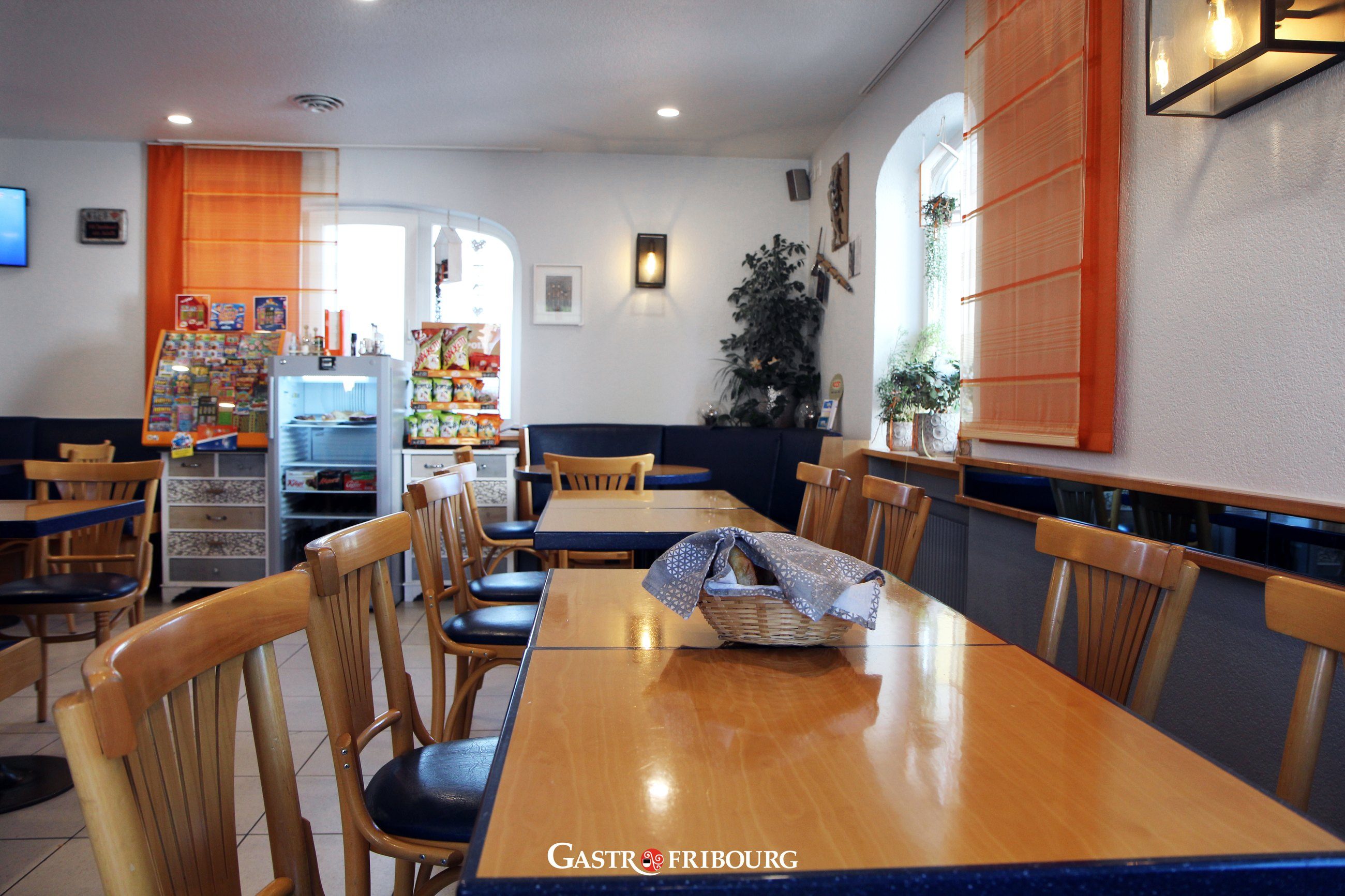 La grande table, les chaises en bois clair et la banquette bleue